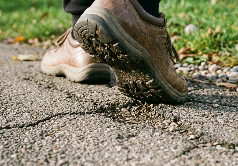 A close-up photo of feet walking on pavement, illustrating a sensory-based grounding exercise to stay in the present moment.