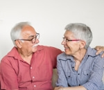 Older couple sitting close on a sofa, smiling at each other during a therapy session in Vaughan