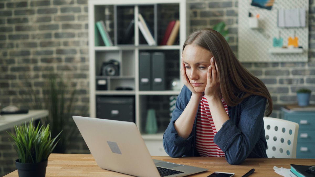 Woman feeling overwhelmed and unable to start a task at a laptop