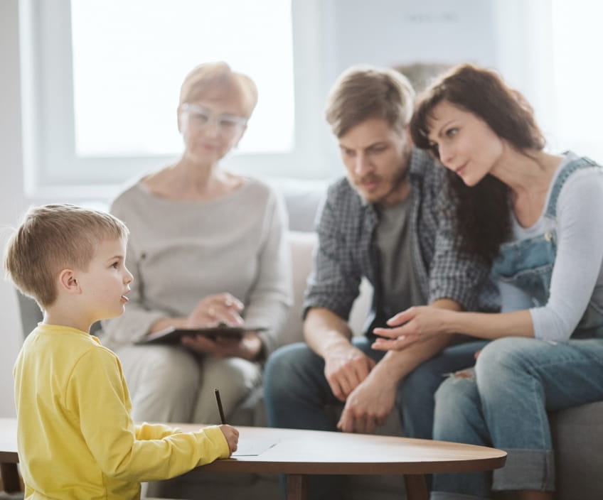 A young boy drawing while his parents speak with a family therapist in Vaughan