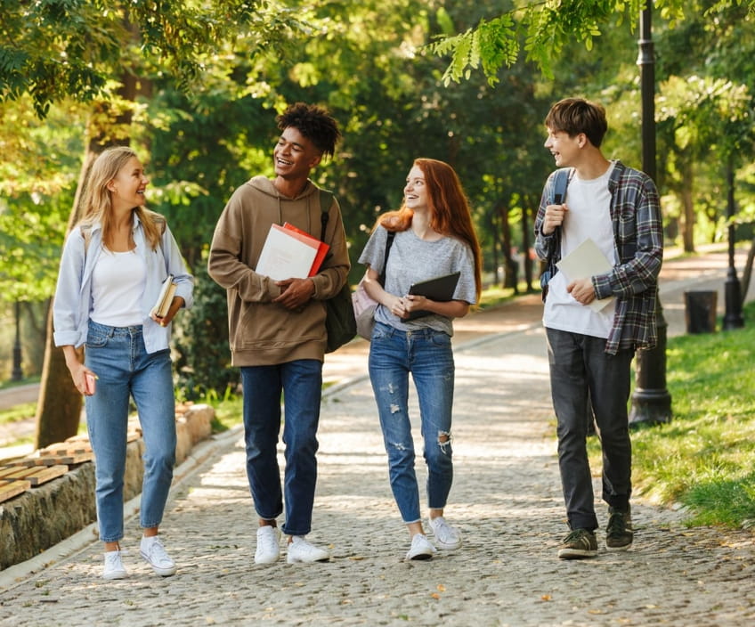 College and university students walking together along a tree-lined campus path