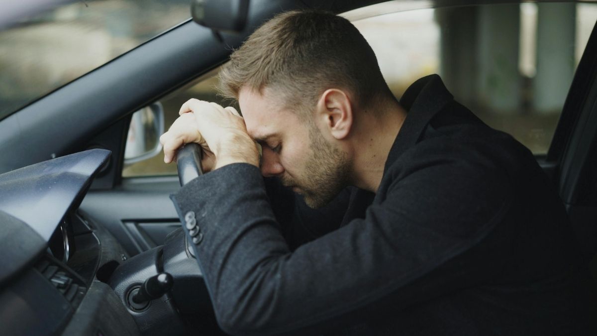 Exhausted man resting his head on the steering wheel after a long commute