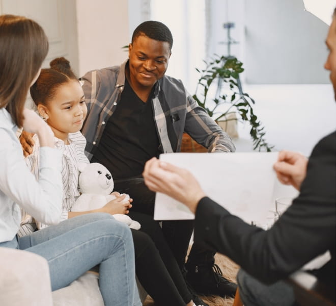 A mother, father and young daughter meeting their therapist for family counselling