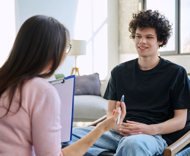 Student talking with a therapist who is taking notes on a clipboard