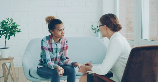 A therapist explaining what cognitive behavioural therapy (CBT) is to a young client