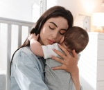 Mother holding her baby close in a quiet nursery, calm and settled