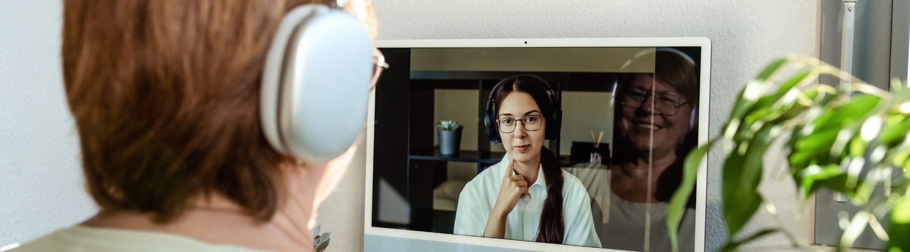 Person in headphones during an online therapy session, with the therapist visible on screen