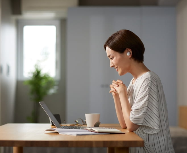 Woman joining a virtual therapy session on a laptop at her kitchen table at home